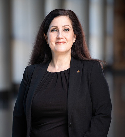 Light-skinned adult with long, straight, brown hair and a black blazer and blouse.